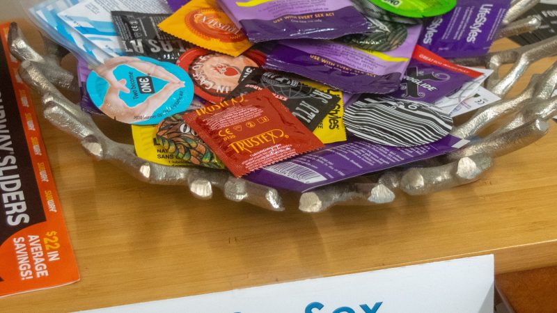 A bowl of condoms with a sign that says Safer Sex Supplies