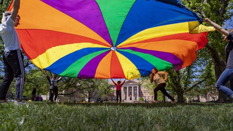 Students play in the quad with a rainbow parachute