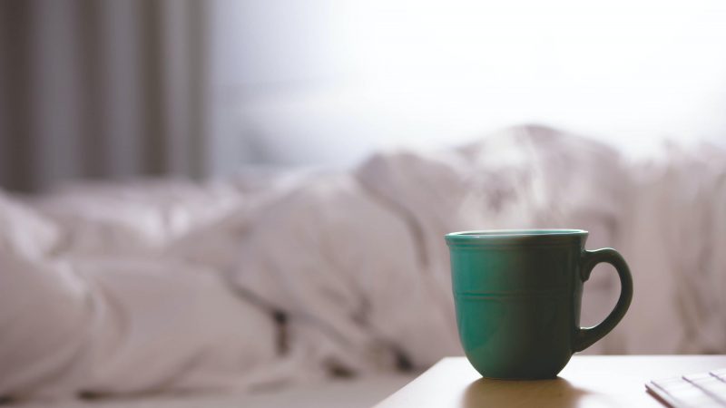 steaming mug next to a bed
