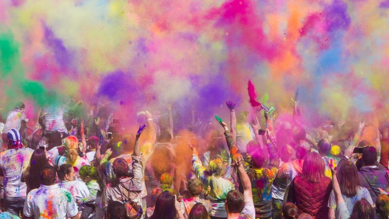 people toss colorful dust in air at Holi