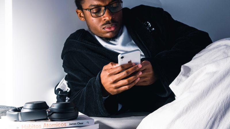 man looks at phone while in bed