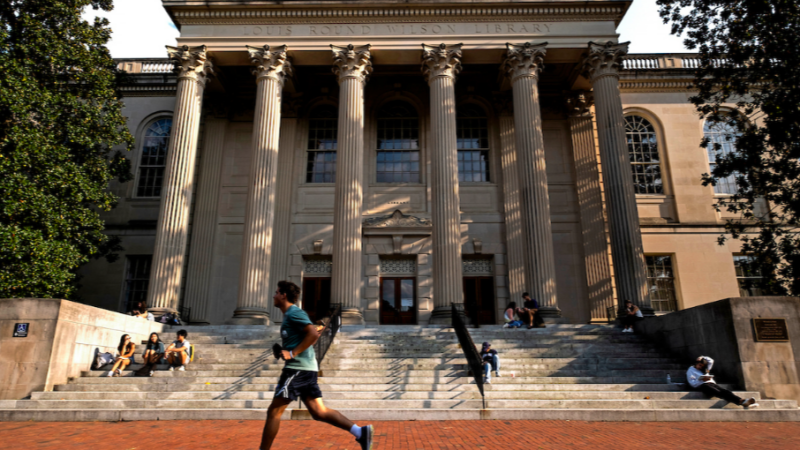 Person in shorts and a t-shirt jogging throught campus near Wilson library.