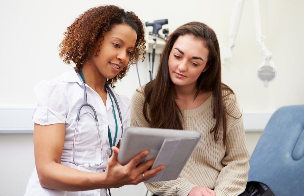 Patient and provider look together at a tablet in an exam room